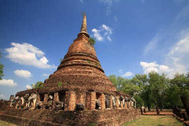 Sukhothai, Tayland 'daki Wat Chang Lom' da mavi gökyüzüne bağlı fil heykelleri olan antik tuğladan bir tapınak. Siyam 'ın ünlü seyahat yeri ve dünya mirası tarihi simgesi.