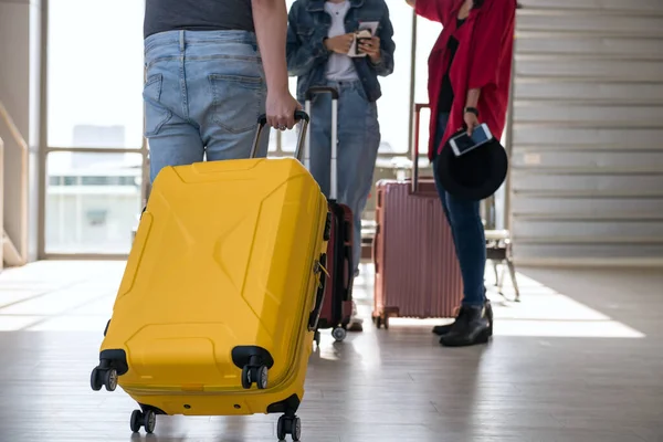 游客拖着黄色的行李去机场候机楼看他的朋友 与年轻伴侣一起旅行或度假的人 图库图片