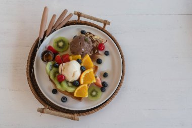Dondurmalı ballı tost ve beyaz ahşap masada karışık meyve..