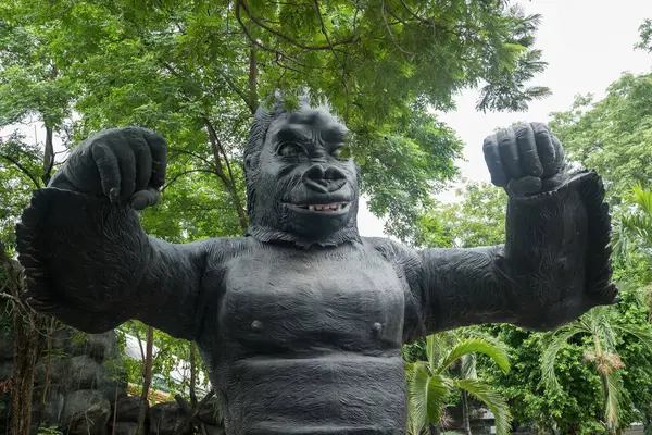Big smiling King Kong statue in outdoor forest amusement park.