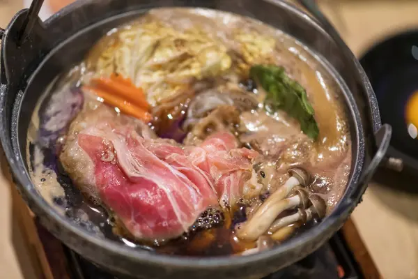 日本寿木汤或沙布汤放在火锅里的芦苇里 顶部看新鲜猪肉的布景 图库照片