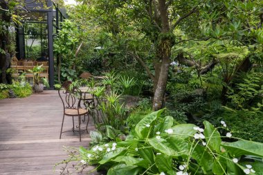 Baharın güzel bahçesinde masası ve sandalyeleri olan açık bir kafe ve restoran. mimari ve park tasarımı.