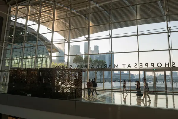 Stock image people inside The Shoppes at Marina Bay Sands with outdoor view during sunset. Famous shopping mall and casino near art museum and garden by the bay.