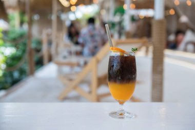 Americano yuzu sütsüz buzlu kahve beyaz masada taze portakal ve modern kafe ve restoranda bulanık müşteriler. Yiyecek ve içecek endüstrisi.
