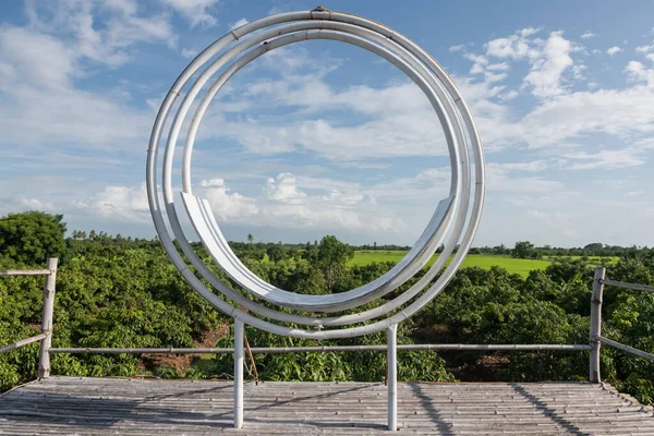 White circle chair for photo shoot with green mango and paddy rice farm view against blue sky in Suphan Buri, Thailand.