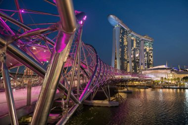 Helix Köprüsü pembe ışığı, Marina Bay Sands Oteli, Singapur, alacakaranlıkta. Ünlü seyahat yeri ya da tatilci.