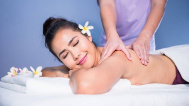 Tayland yağı sırt ve omuz masajı. Genç Asyalı güzel kadına. Yatakta tesisatçılık çiçeği olan spa salonunda. Masözün vücut bakımı uygulaması. Alternatif sağlık sektörü