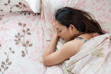 Asyalı genç ve güzel bir kadının portresi. Evde yatakta uyuyor. Çinli kız biraz kestir..