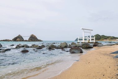 View of Sakurai Futamigaura couple stones and white torii gate in Itoshima, Fukuoka Prefecture, Japan. It is one of famous travel destination or sightseeing spots in Itoshima.