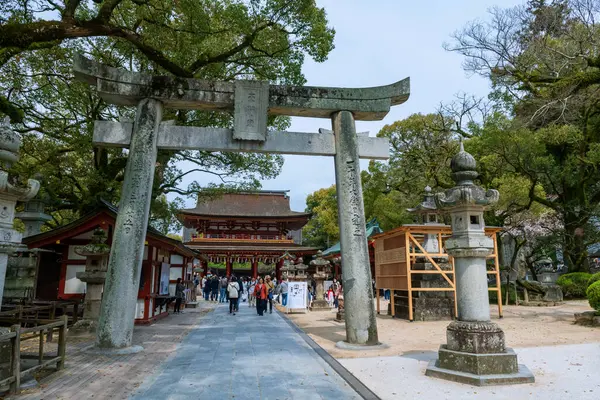 Fukuoka, Japonya - 30 Mar 2024: Turistler Torii kapısından ve Dazaifu Tenmangu Tapınağı 'nın ana girişinden. Eğitim Tanrısı Sugawara Michizane 'nin ruhuna adanmış ünlü seyahat yeri..