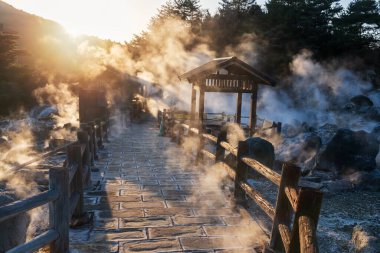 Silhouette landscape of mount Unzen Hell valley Jigoku and hot springs at sunset with heavy gas steam by Shimabara city, Nagasaki, Kyushu, Japan. Hot water, gases and steam spout out of the earth. clipart