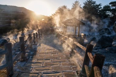 Jigoku Dağı Dağı ve gün batımında Shimabara şehri Nagasaki, Kyushu, Japonya 'nın yoğun gaz buharı ile kaplanan kaplıcaları. Sıcak su, gaz ve buhar topraktan fışkırıyor.