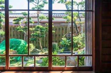 Koi no Mizube Michi, Shimabara, Nagasaki, Japonya 'daki kafe ve restoran penceresinden Japon bahar bahçesi manzarası. Sazan balığının şehir boyunca temiz bir kanalizasyon suyunda yüzüşünü izlemek için ünlü bir seyahat yeri..