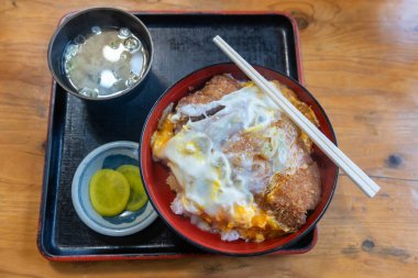 Katsudon, bol yağda kızartılmış domuz pirzolası tonkatsu ile tepesinde yumurta ve ahşap masada miso çorbası. Meşhur Japon yemekleri..