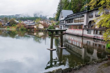 Antik Torii kapısı Kinrin Gölü üzerinde ilkbaharda Yufu Dağı 'nın manzaralı bir yerinde, Yufuin, Oita Bölgesi, Kyushu, Japonya. Meşhur seyahat noktası.