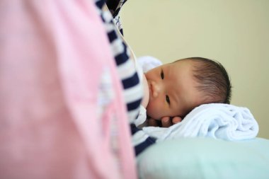Anne, doğum ameliyatından sonra yeni doğan Asyalı erkek bebeğe anne sütü veriyor. Annelik görevi..