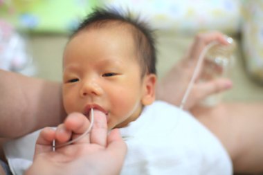 Küçük bir tüp kullanarak Sarılık Asyalı yeni doğan erkek bebeğe anne sütü içiriyorum. Sarılık kanı, kırmızı kan hücrelerinin sarı pigmenti olan bilirubin fazlalığını içerir..