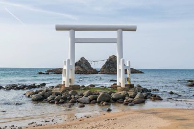 Itoshima, Fukuoka Bölgesi, Japonya 'daki Sakurai Futamigaura' da beyaz torii kapısı ve birkaç taş. Ünlü seyahat yeri ya da turistik yerler.