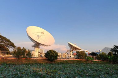 Dev uydu anteni ya da radyo antenleri radyo teleskopu dalgaları için gün batımında Lotus göletinin yanındaki mavi gökyüzüne karşı..