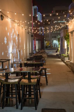 Açık bar masaları ve geceleri ışıklandırılmış sandalyeler, Singapur 'un Bugis köyü. Gece hayatı için ünlü bir seyahat yeri..