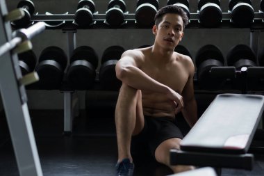 Spor salonunda dambıl egzersizinden sonra çıplak gövdesi olan yakışıklı Asyalı adamın portresi. Vücut geliştirme ve sağlıklı yaşam.