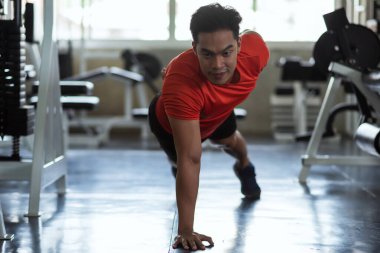 Jimnastik salonunda tek elle göğüs şınavı çeken güçlü bir Asyalı genç. Vücut geliştirme ve sağlıklı yaşam tarzı konsepti için kas egzersizi.