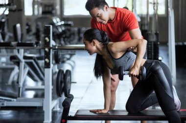 Kişisel antrenör portresi, spor salonundaki güzel Asyalı kadın için Aptal pazı egzersizi için kol pozisyonunu ayarlar. Mutlu Asyalı çift vücut geliştirme ve sağlıklı yaşam için egzersiz yapıyor..