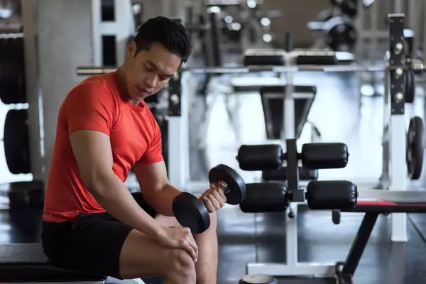 stock image Portrait of muscle Asian fit man exercise heavy dumbbells on left hand in fitness gym. Muscular body sportsman. Bodybuilding and healthy sport lifestyle concept.