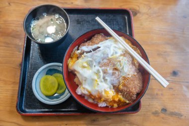 Katsudon bol yağda kızartılmış domuz pirzolası üzerine pirinçle yumurta ve ahşap masada miso çorbası. Meşhur Japon yemekleri..