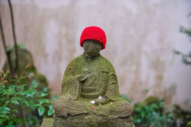 Japonya, Fukuoka 'daki Nanzoin Tapınağı' nda kırmızı örülmüş kumaş şapka giyen Jizo Buddha heykeli. Sasaguri 'deki Shingon Budist Tapınağı' nda dünyanın en büyük bronz heykelinin ünlü seyahat yeri..