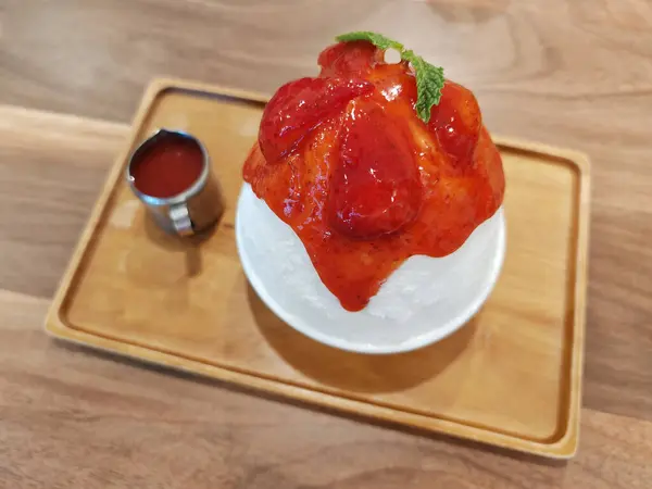 stock image Korean shaved ice dessert with big strawberry and sweet sauce on wooden table in cafe and restaurant. Sweet dessert with unhealthy eat concept.