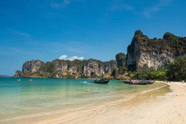 Kireçtaşı dağı, turkuaz andman denizi ve Tayland, Krabi 'de mavi gökyüzü olan bir sürü ahşap turist teknesi olan Railay plajı. Ünlü tatilci ya da Siam 'daki yaz gezisi merkezi.