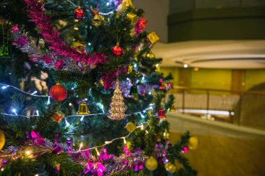 Taşaklı bir Noel ağacı, parlak bir çelenk ve gece vakti modern bir otel binasının arka planında süslemeler. Noel kutlaması.