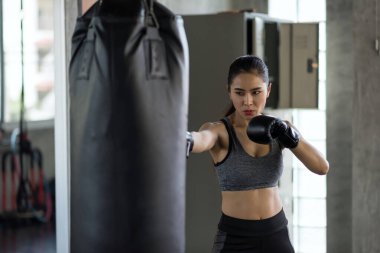 Güçlü Asyalı atlet kadın spor salonunda kum torbasına vurdu. Vücut geliştirme ve sağlıklı yaşam tarzı konsepti için Muay Thai eğiten atletik bir kız. Spor kulübünde egzersiz..