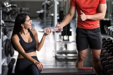 Spor salonundaki halter egzersizinden sonra güzel Asyalı kadına başparmağını kaldırıp su ver. Mutlu Asyalı çift vücut geliştirme ve sağlıklı yaşam için egzersiz yapıyor..