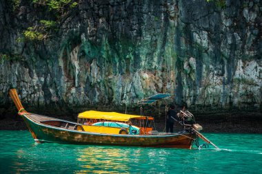 long tail wooden boat over turquoise andaman sea at Loh Samah Bay of Pileh in Krabi, Thailand. Famous travel destination or summer holiday maker at tropical country, Siam. clipart