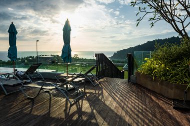 Rooftop bedchairs against sunset light with beautiful view of andaman sea, Phuket, Thailand. place for sunbath to get tan at luxury hotel. clipart