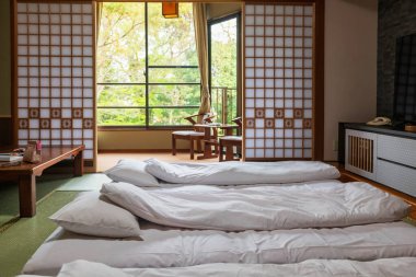 Traditional Japanese tatami bedroom and chairs by windows at balcony with spring garden view of ryokan hotel, Yanagawa, Fukuoka, Japan. clipart