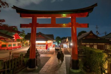 Hareketçiler, Fushimi Inari Taisha türbesinin Dev Torii kapısından sonbahar renklerinde Japonya 'nın Kyoto şehrinde gece aydınlanarak geçiyorlar. Kansai 'deki binlerce Torii Kapısı için sonbahar sezonunda ünlü seyahat yeri..