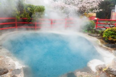 Japonya, Beppu 'da şiddetli yağmur, gaz ve kiraz çiçekleri eşliğinde Kamado Jigoku' nun mavi kaplıcası. Burası Onsen kaplıcaları ve 8 büyük jeotermal sıcak nokta, 8 cehennem dolusu Beppu ile ünlüdür..