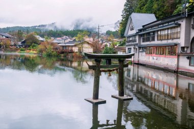 İlkbaharda Yufu Dağı 'nın manzaralı bir yerinde Kinrin Gölü üzerindeki Torii Kapısı' nda kiraz sakura çiçeği, Oita, Kyushu, Japonya. Meşhur seyahat yeri Yufuin 'in simgesi.
