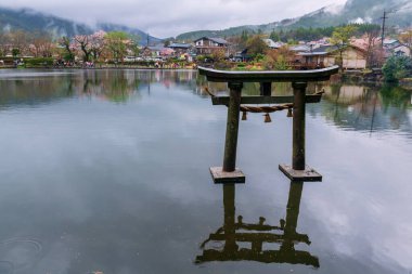 Sabah sisi olan ve Kinrin Gölü 'nde kiraz çiçeği sakura ağacıyla yağmur yağan yerel bir otel. Oita Bölgesi, Kyushu 'da Yufuin' in ünlü tatil beldesi..
