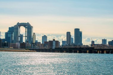 Osaka, Japonya - 11 Aralık 2024: Yodogawa Nehri 'nden geçen Hankyu Demiryolu treni Umeda gökyüzü binası ve şehir manzaralı. En tepedeki manzaralı şehri görmek için ünlü bir seyahat yeri..