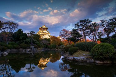 Osaka Kalesi manzarası, Japonya, Kansai 'de, alacakaranlıkta, gölette ufuk çizgisi yansıması olan bir bahçe. Sonbahar mevsiminde Kansai 'yi gezmek için ünlü bir tatil beldesi..