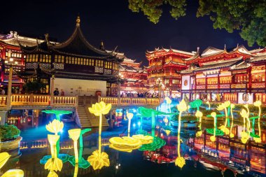 Güzel Yuyuan bahçe alışveriş merkezi ve yapay nilüfer ya da nilüfer çiçekleri gece yansıması ile gölette parlıyor.