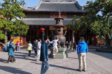 Çinli kadın şans getirmesi için Longhua Tapınağı 'ndaki metal konteynıra para atmaya atladı. Maitreya Buddha 'nın Budist tapınağı, Song hanedanlığının mimari tasarımı..