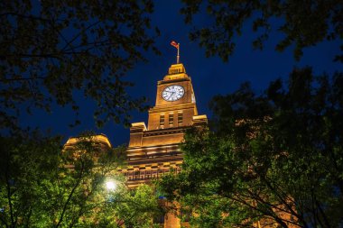 Çin yüzyıllık saat kulesi Huangpu Nehri 'nin yanındaki Bund' un ağaç gövdesine sahip gece, Şanghay, Çin. Modern kasabanın ünlü alışveriş ve görülme yeridir..