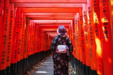 Fushimi Inari Taisha tapınağının Torii kapı kemerinde kimonolu genç bir Japon kadın. Bin Torii Kapısı için seyahat yeri.