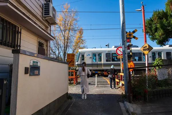 İnsanlar JR Treni 'nin sonbaharda Tofukuji istasyonuna giden kavşağı geçmesini bekliyor. Japonya demiryolu ağının ve banliyö demiryolu hizmetinin JR Grup hatları.