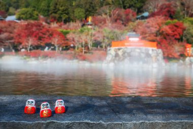 Daruma bebekleri gölün kenarında bulanık sonbahar bahçesi ve Katsuo-ji tapınağı, Minoh, Osaka, Japonya 'nın tapınağı. Sonbaharda Kansai 'yi görmek için ünlü bir seyahat yeri. Zafer tapınağı.